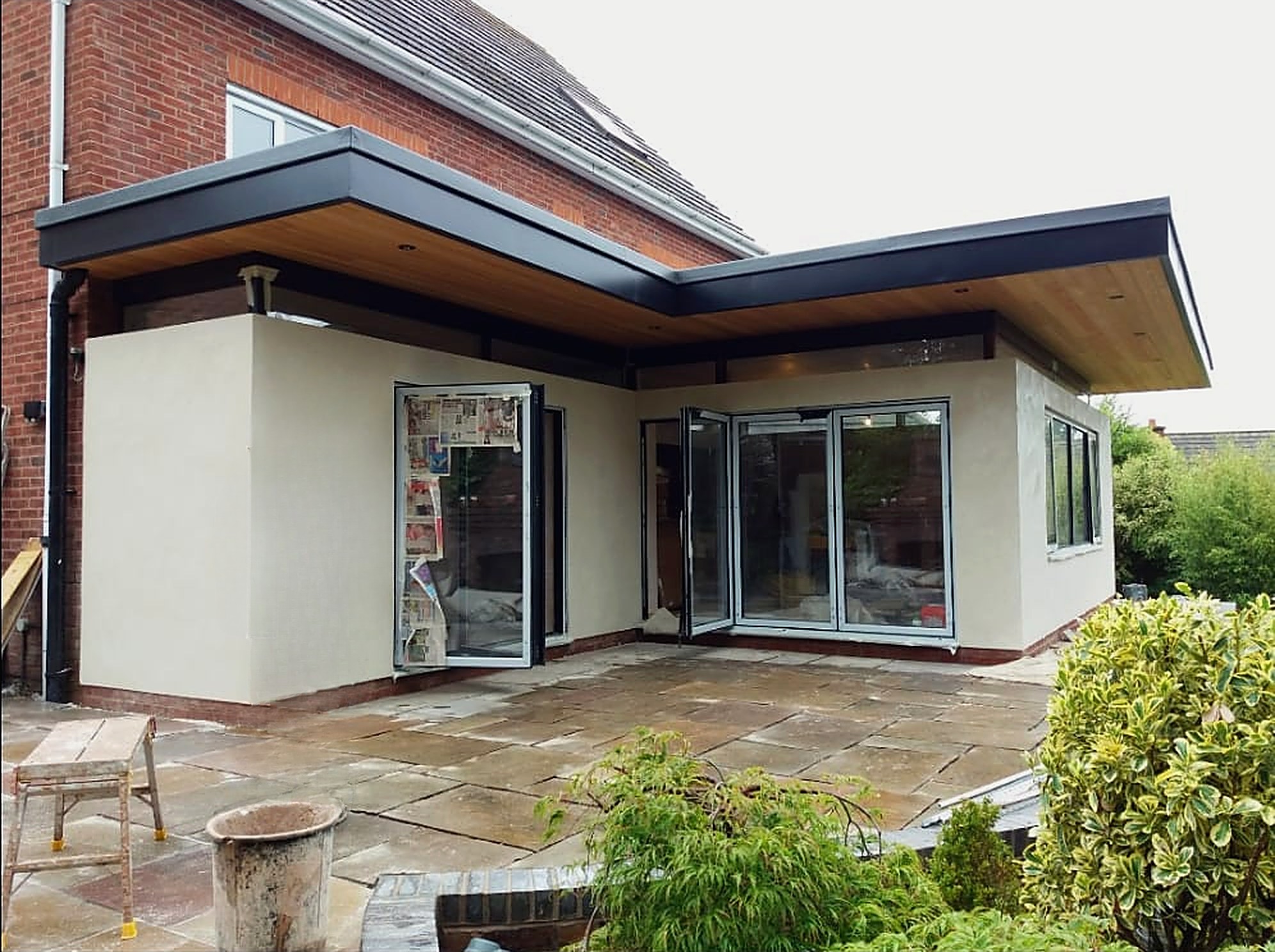 L shaped single storey extension with a flat roof, timber soffit and bi-fold doors