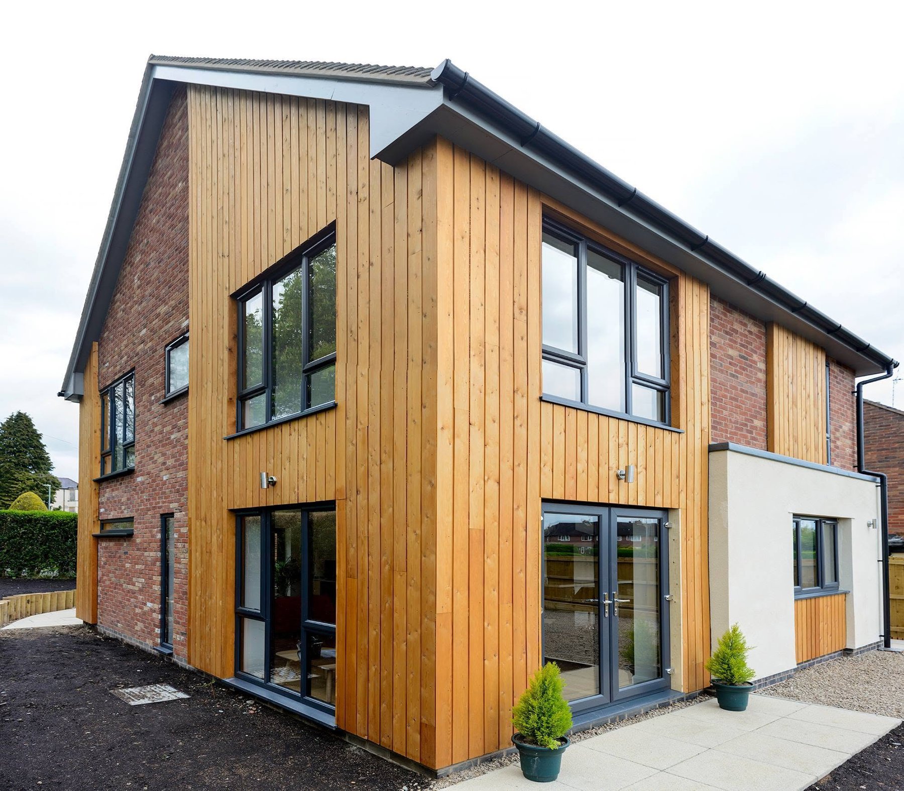 Two storey new build house in red brick and vertical timber cladding
